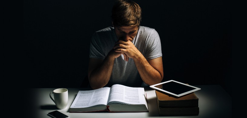 student sadly looking over books and tablet