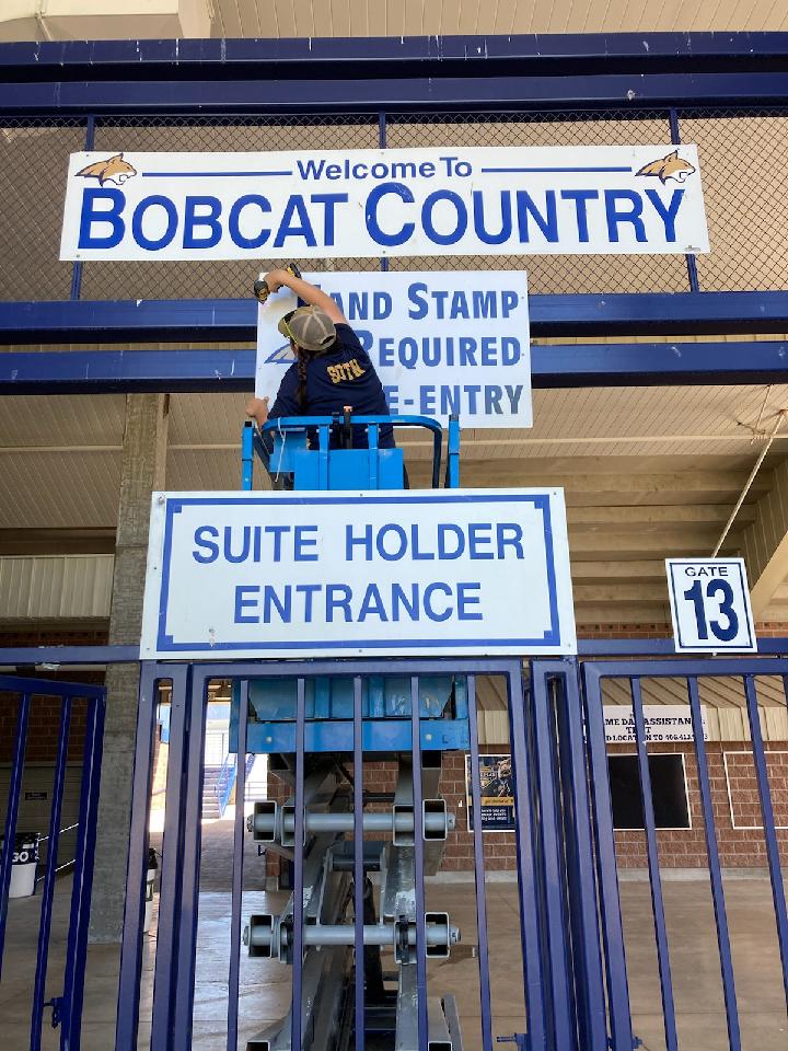 Student employee putting up a sign at a football game