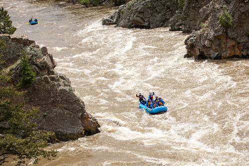 Two blue rafts with people floating down the Yellowstone River