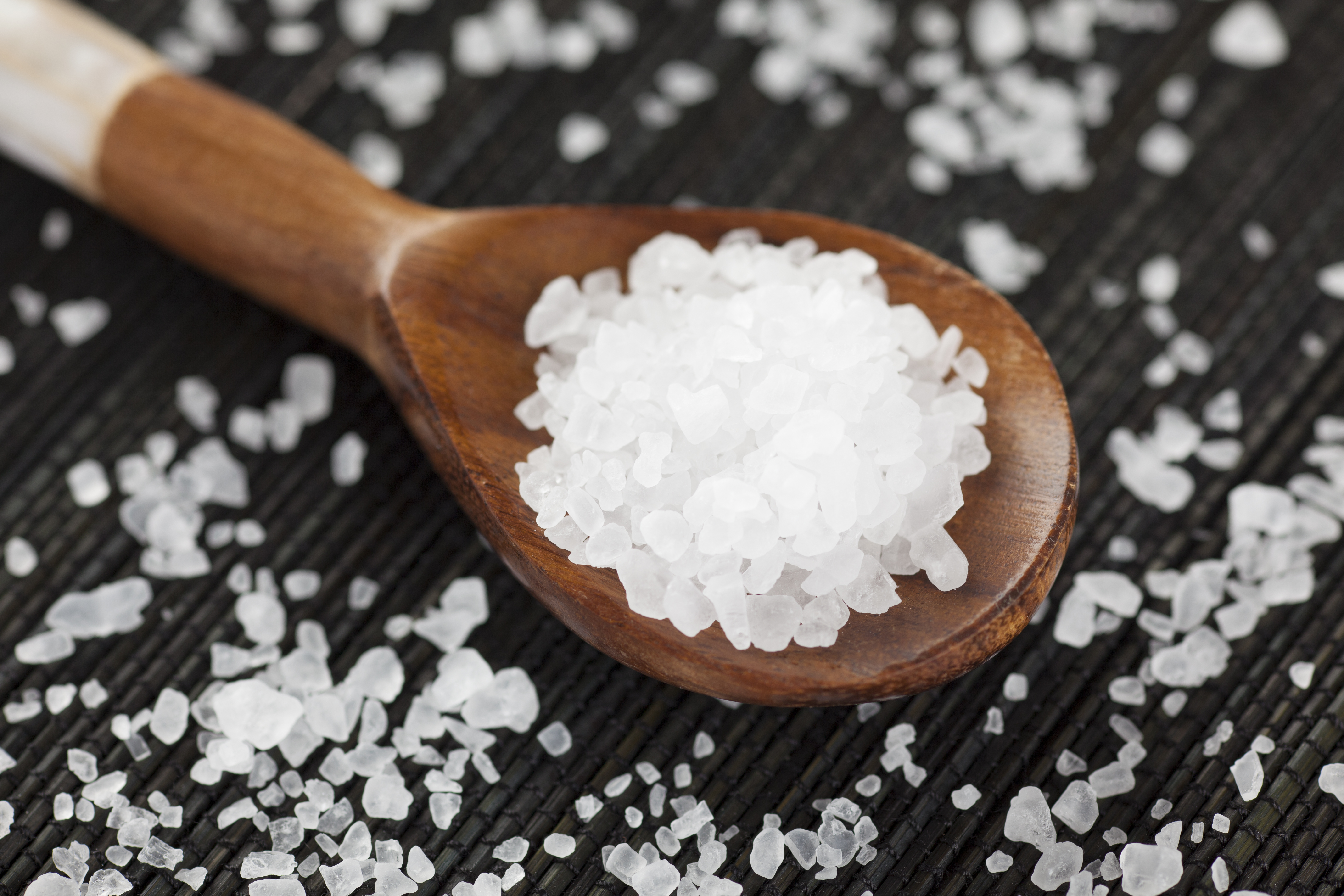 A wooden spoon with salt granules.