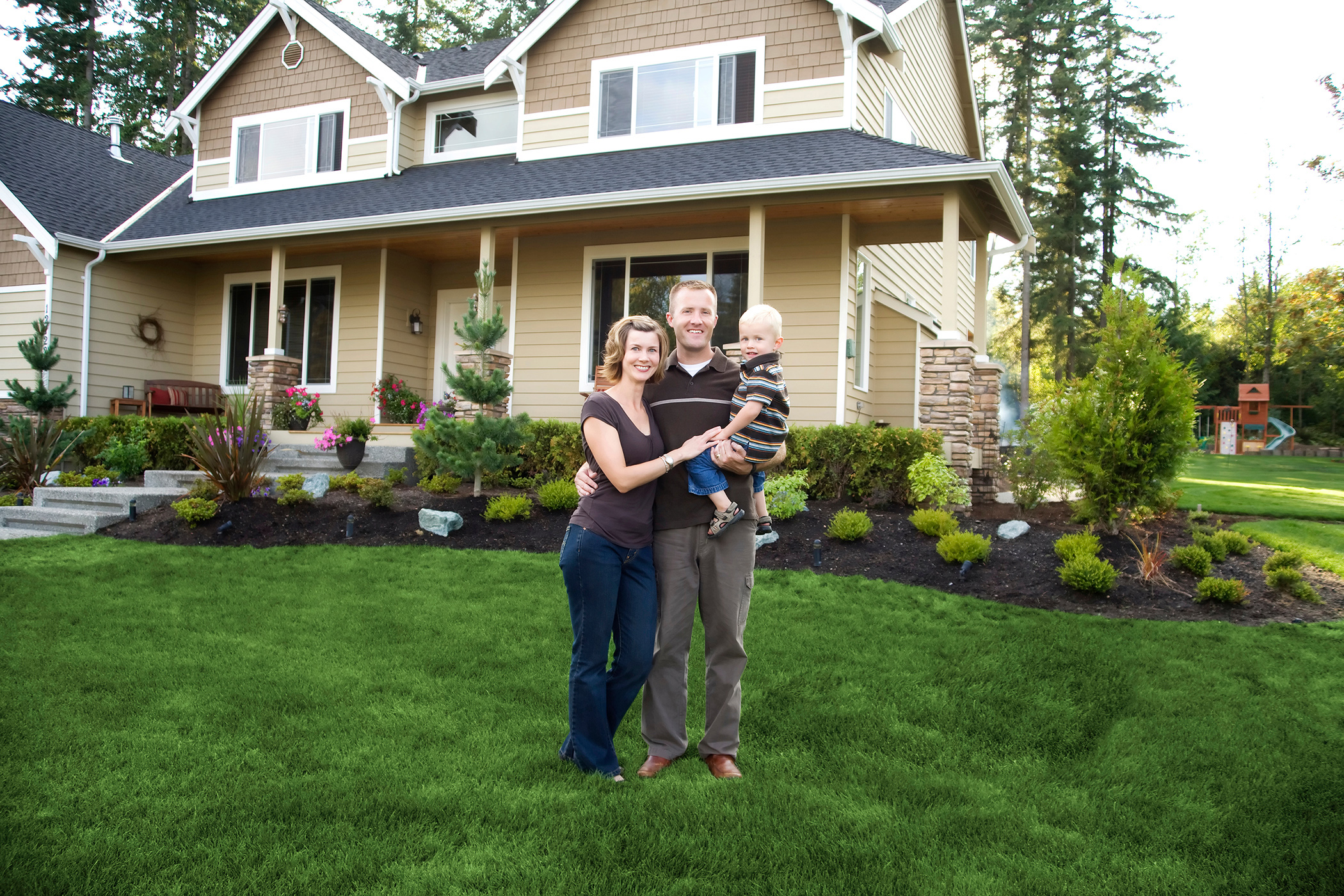 Young family standing in front of their home.