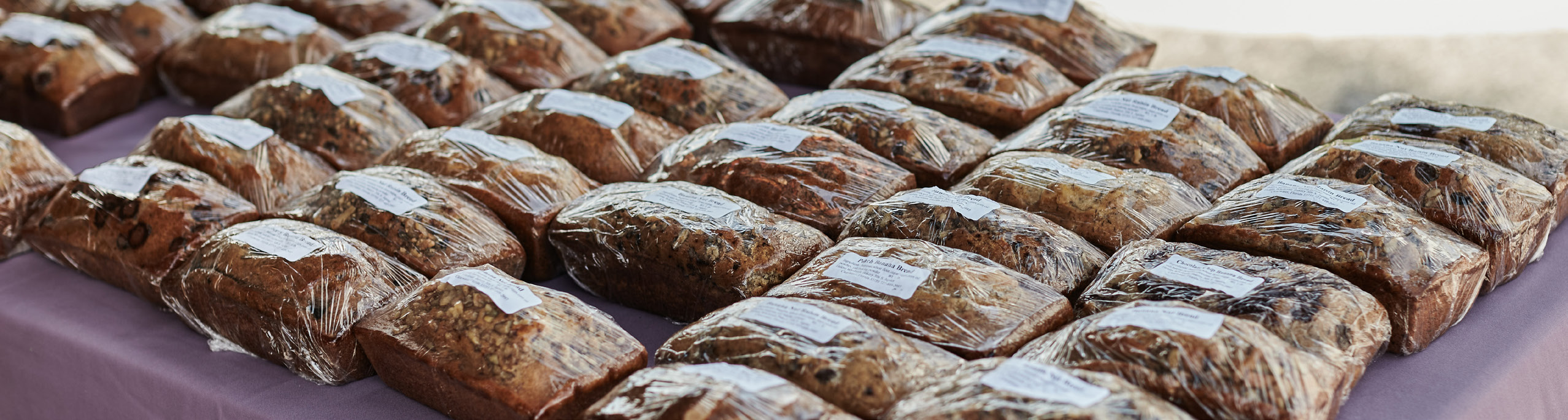 Table with neatly wrapped loaves of bread, placed in rows.