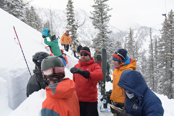 Snow and Avalanche Lab director Jordy Hendricks stands in a snow pit, speaking while students collect data